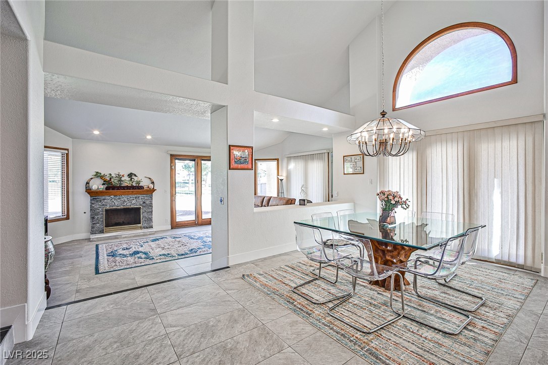 7772 Boca Raton Drive Las Vegas, NV 89113 - Photo 17 of 40 Dining area with a fireplace, high vaulted ceiling, a chandelier, recessed lighting, and light tile patterned floors