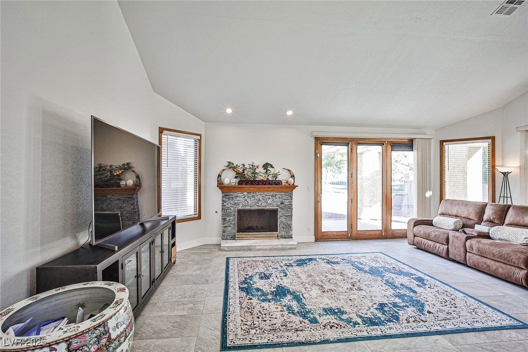 7772 Boca Raton Drive Las Vegas, NV 89113 - Photo 19 of 40 Living area with vaulted ceiling, a stone fireplace, plenty of natural light, and recessed lighting