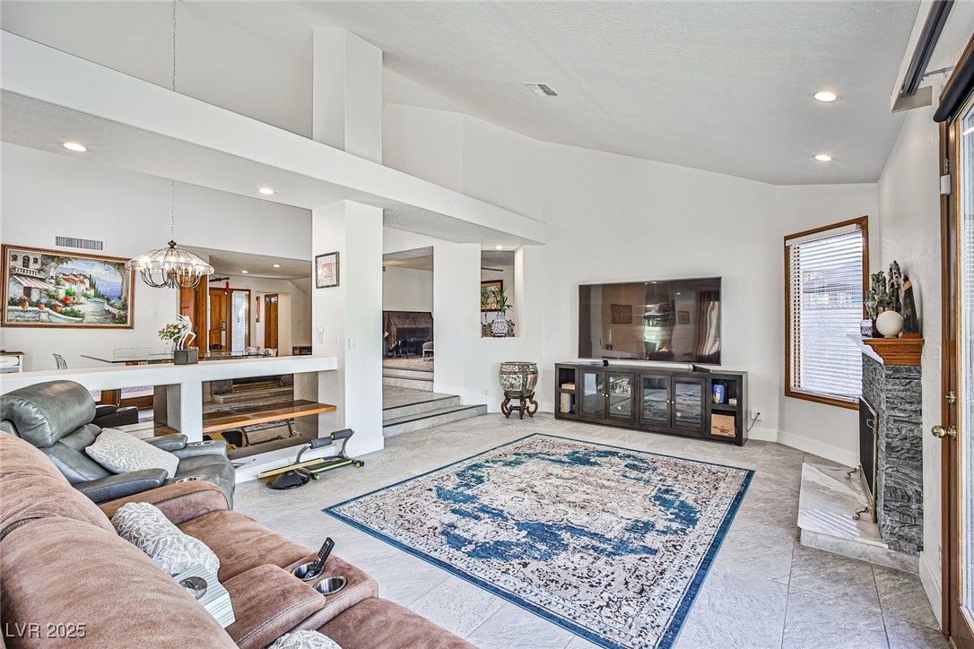 7772 Boca Raton Drive Las Vegas, NV 89113 - Photo 22 of 40 Living area with a fireplace with raised hearth, recessed lighting, high vaulted ceiling, a chandelier, and light tile patterned floors