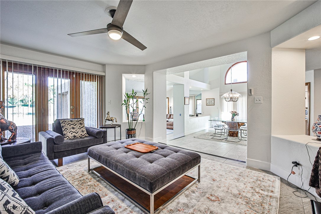 7772 Boca Raton Drive Las Vegas, NV 89113 - Photo 23 of 40 Living room featuring healthy amount of natural light, a ceiling fan, and a chandelier