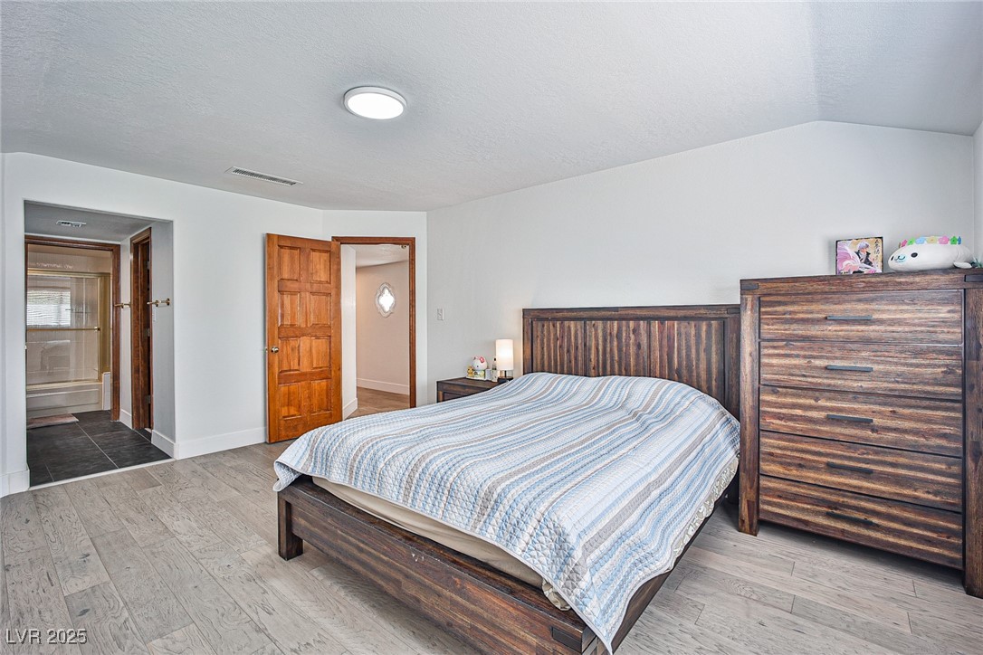 7772 Boca Raton Drive Las Vegas, NV 89113 - Photo 26 of 40 Bedroom featuring light wood finished floors, a textured ceiling, and ensuite bathroom