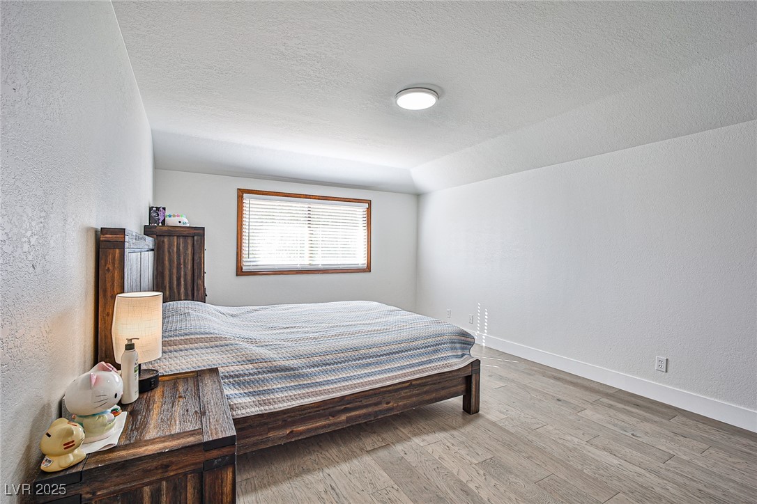 7772 Boca Raton Drive Las Vegas, NV 89113 - Photo 27 of 40 Bedroom with a textured wall, light wood finished floors, and a textured ceiling