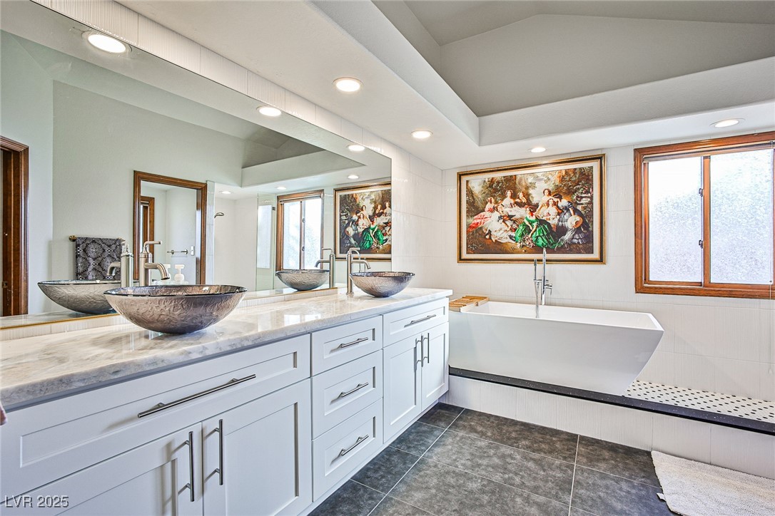7772 Boca Raton Drive Las Vegas, NV 89113 - Photo 33 of 40 Full bathroom featuring recessed lighting, a freestanding bath, double vanity, dark tile patterned floors, and tile walls