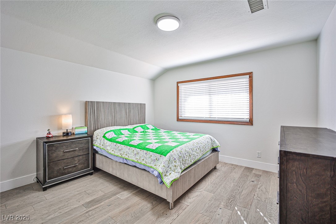 7772 Boca Raton Drive Las Vegas, NV 89113 - Photo 39 of 40 Bedroom featuring light wood-style floors, a textured ceiling, and lofted ceiling