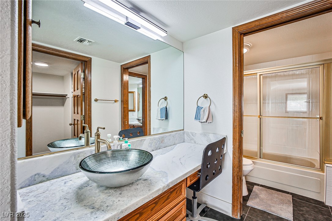 7772 Boca Raton Drive Las Vegas, NV 89113 - Photo 40 of 40 Full bathroom with vanity, shower / bath combination with glass door, a textured ceiling, and dark tile patterned flooring