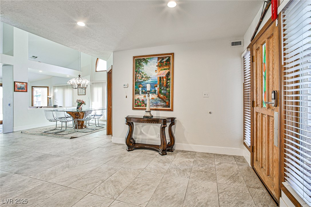 7772 Boca Raton Drive Las Vegas, NV 89113 - Photo 9 of 40 Corridor featuring recessed lighting, a textured ceiling, light tile patterned flooring, and a chandelier