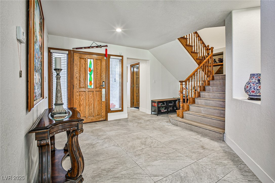 7772 Boca Raton Drive Las Vegas, NV 89113 - Photo 10 of 40 Entryway with a textured wall, stairs, and light tile patterned floors