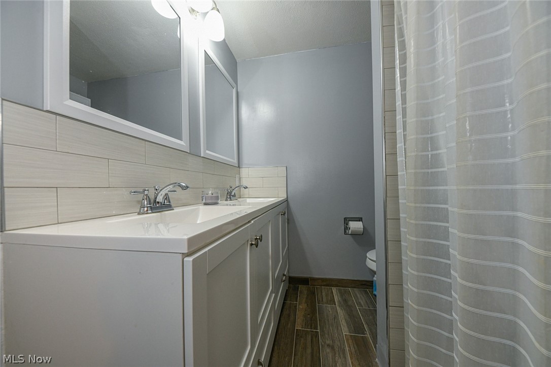 1275 Sandy Lake Road Ravenna, OH 44266 - Photo 23 of 34 Renovated upstairs full bath with double sink vanity, subway tile backsplash and updated wood-look tile floor.