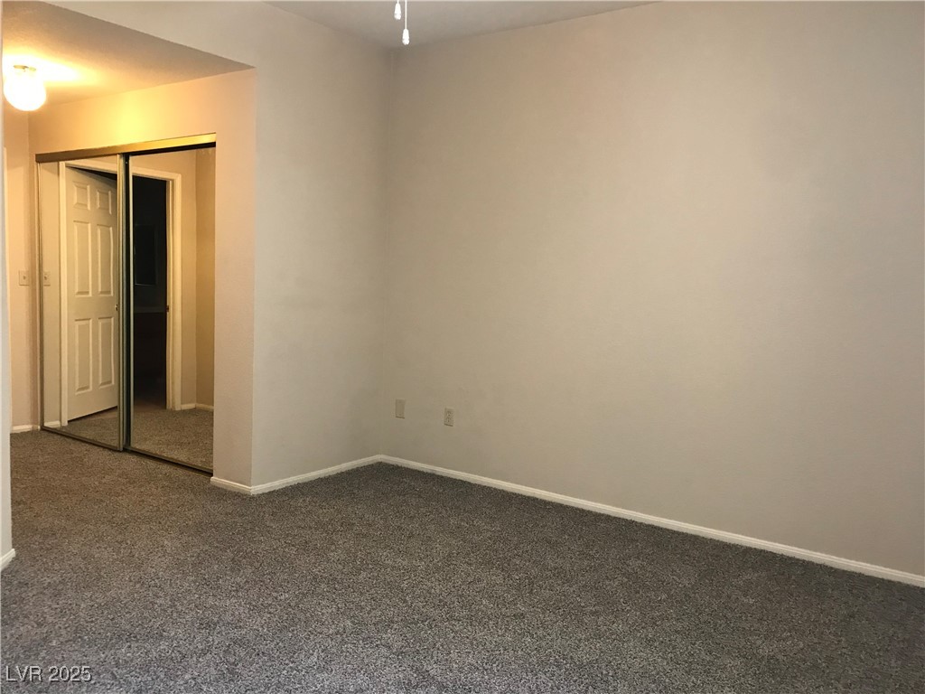 5155 West Tropicana Avenue, Unit 1155 Las Vegas, NV 89103 - Photo 9 of 11 Unfurnished bedroom with dark colored carpet and a closet