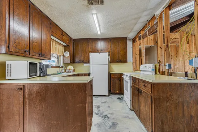 a kitchen with granite countertop cabinets stainless steel appliances a sink and a refrigerator