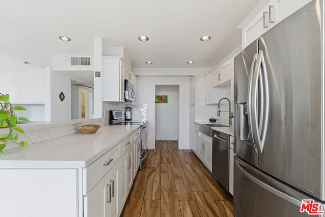 a kitchen with stainless steel appliances a refrigerator sink and wooden floor