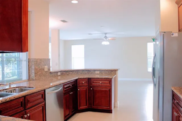 a kitchen with stainless steel appliances granite countertop a refrigerator and a sink