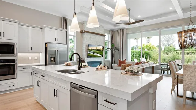 a kitchen with kitchen island granite countertop a sink appliances cabinets and a large window