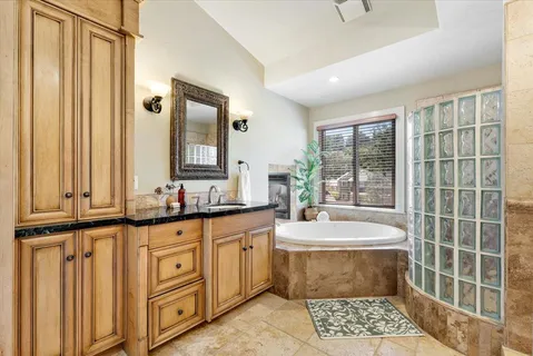 a bathroom with a granite countertop sink a mirror and a bathtub