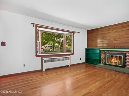 a view of an empty room with a window and wooden floor