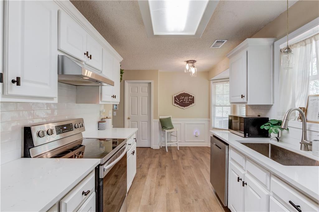 925 Nature Trail Bethlehem, GA 30620 - Photo 15 of 41 a kitchen with stainless steel appliances a sink dishwasher stove refrigerator and white cabinets with wooden floor
