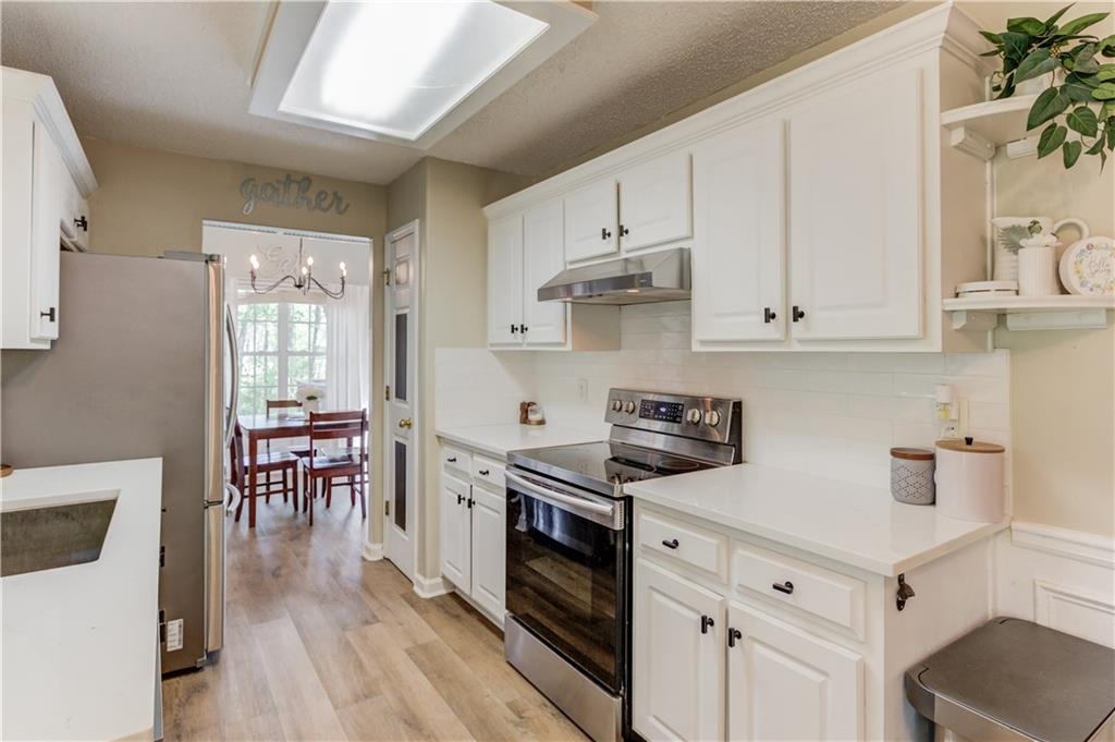 925 Nature Trail Bethlehem, GA 30620 - Photo 16 of 41 a kitchen with granite countertop a stove top oven a sink dishwasher and white cabinets with wooden floor