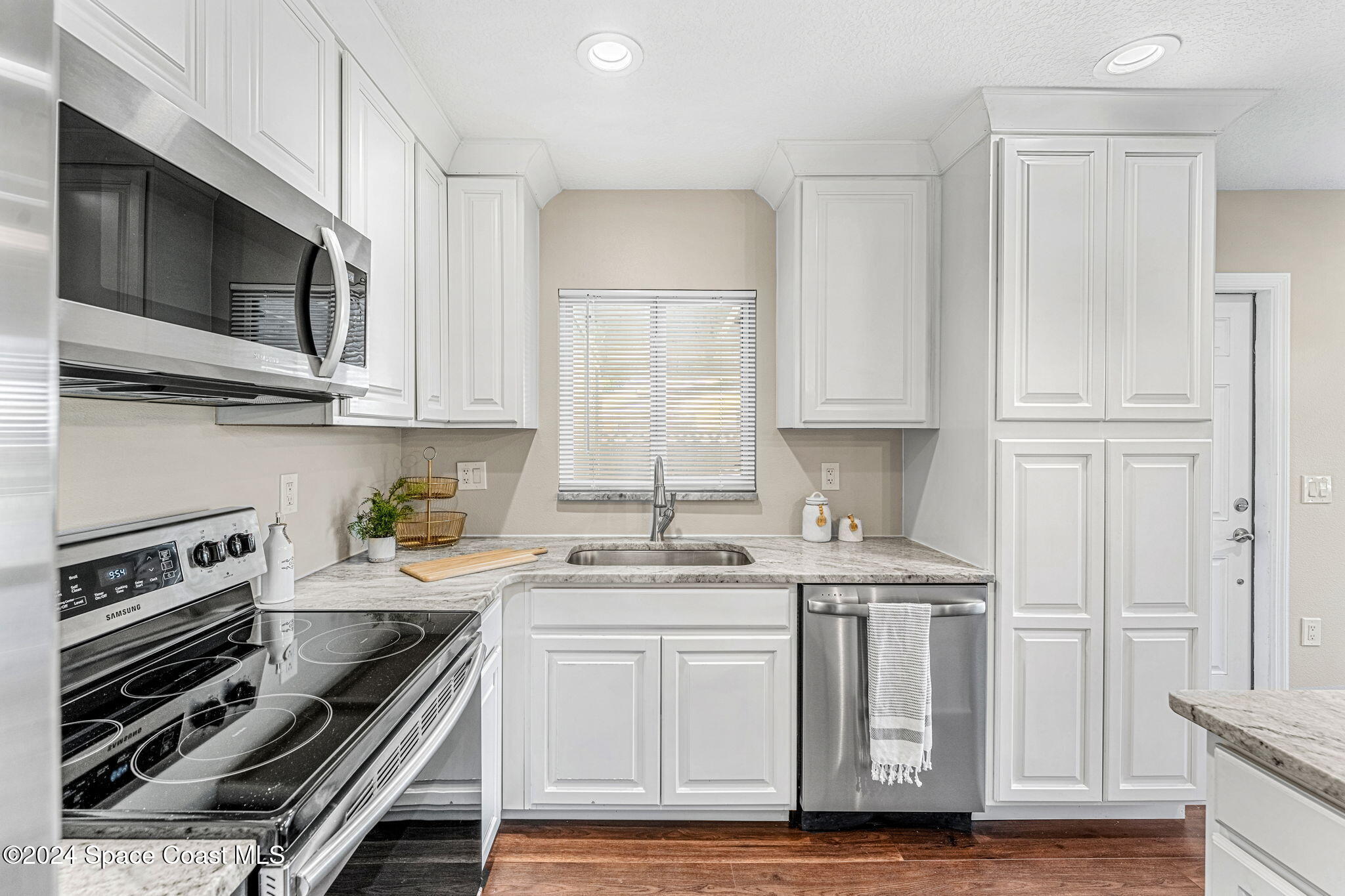 5120 Sutton Avenue Melbourne, FL 32904 - Photo 7 of 38 a kitchen with stainless steel appliances white cabinets and stove top oven