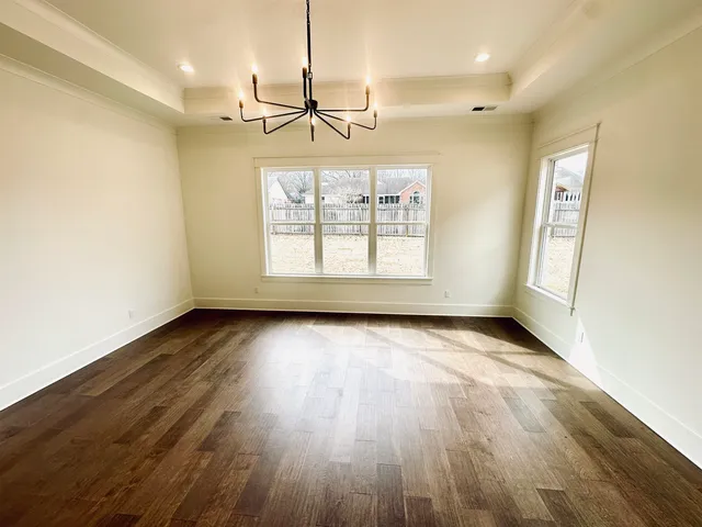 an empty room with wooden floor exposed radiator and windows