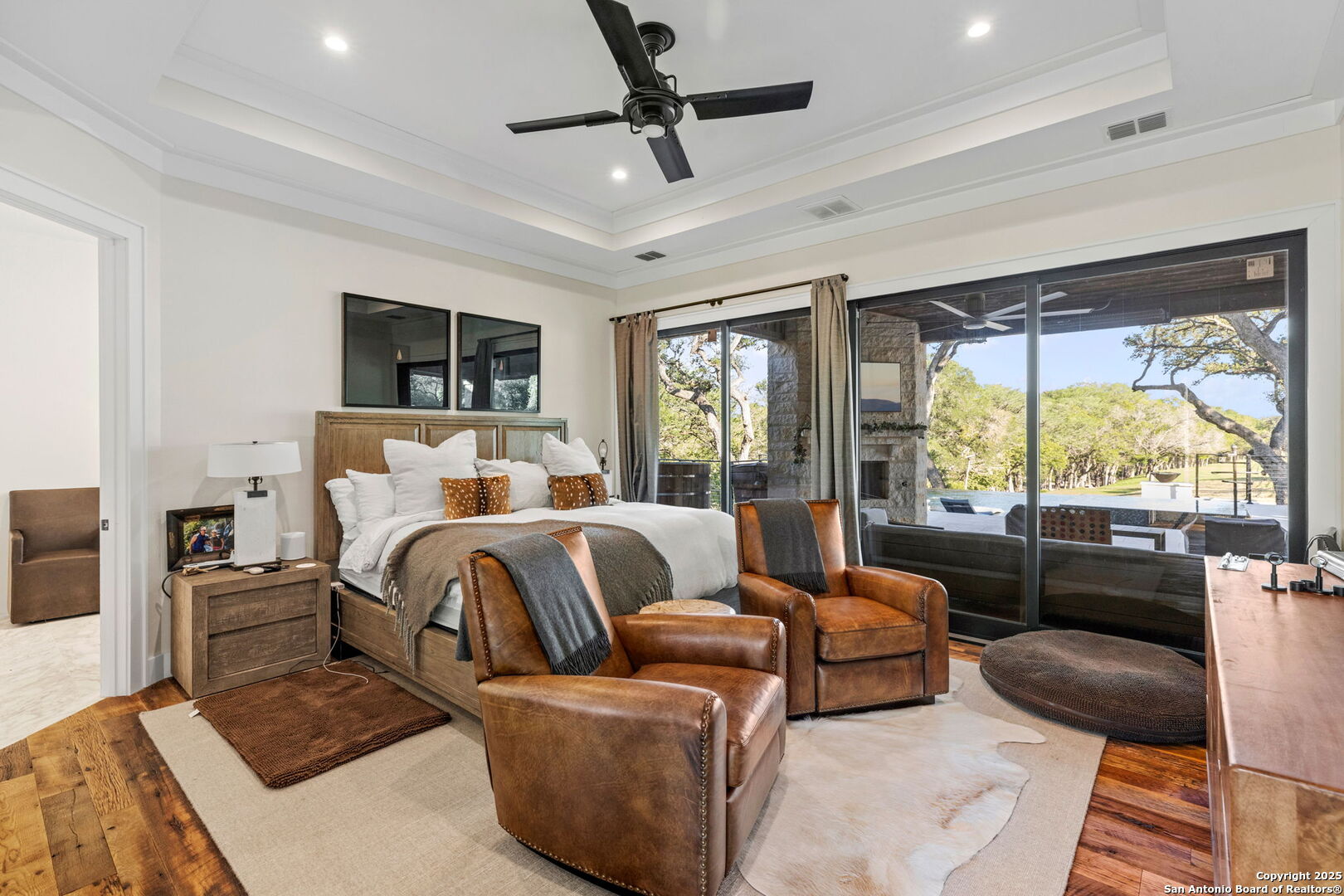 1146 Sisterdale Road Boerne, TX 78006 - Photo 13 of 94 a bedroom with a large bed a flat screen tv and a large window