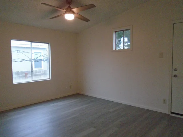 a view of empty room with wooden floor and fan