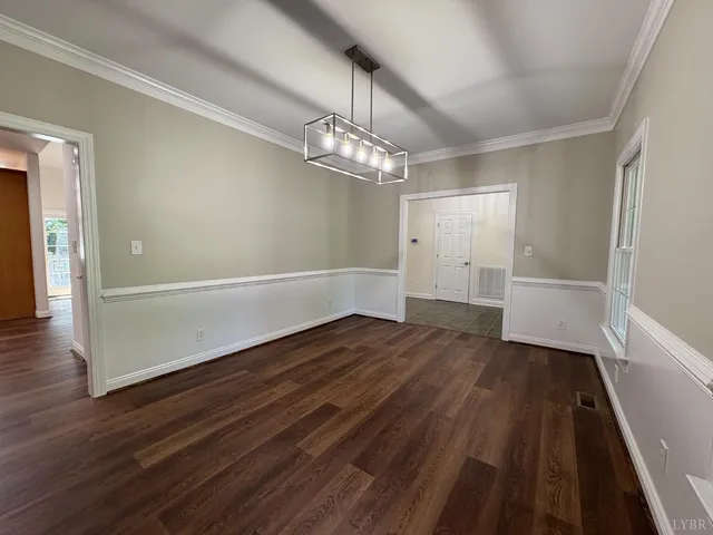 a view of an empty room with wooden floor and staircase