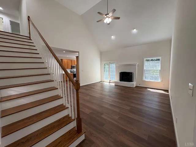 a view of an empty room with wooden floor fireplace and a window