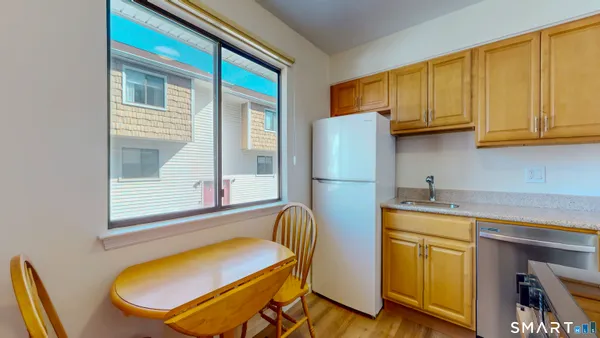 a kitchen with stainless steel appliances granite countertop a refrigerator a stove and white cabinets with wooden floors