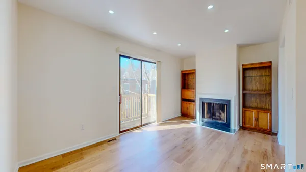 an empty room with wooden floor fireplace and windows