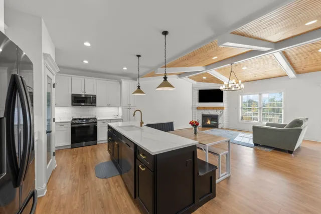 a kitchen with granite countertop a stove a sink dishwasher a refrigerator and a fireplace with wooden floor