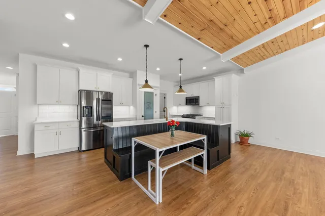 a kitchen with stainless steel appliances kitchen island granite countertop a table chairs stove and white cabinets