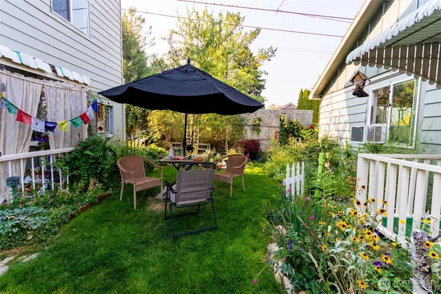 a view of a chair and table with umbrella in backyard
