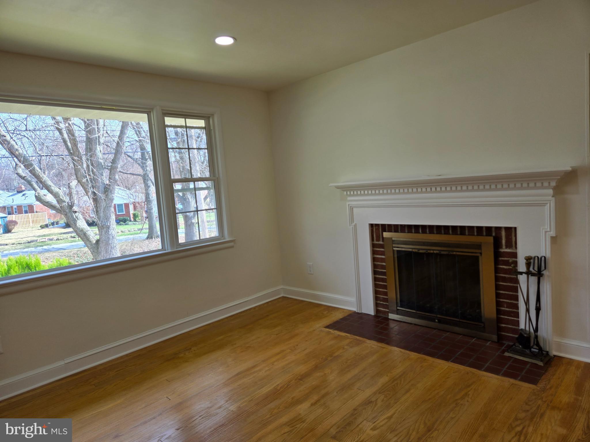 10500 Glenhaven Drive Silver Spring, MD 20902 - Photo 7 of 21 an empty room with wooden floor fireplace and windows