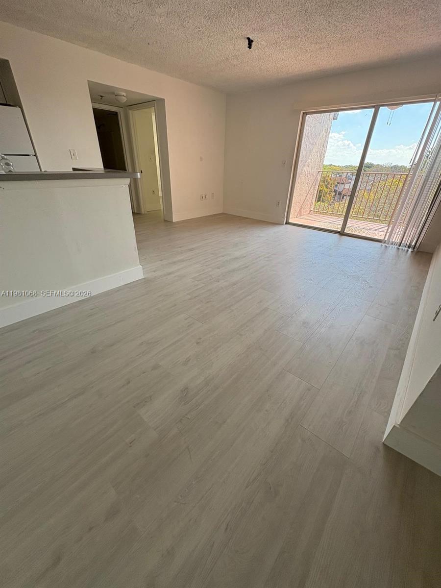 15231 Southwest 80th Street, Unit 615 Miami, FL 33193 - Photo 2 of 3 an empty room with wooden floor and windows