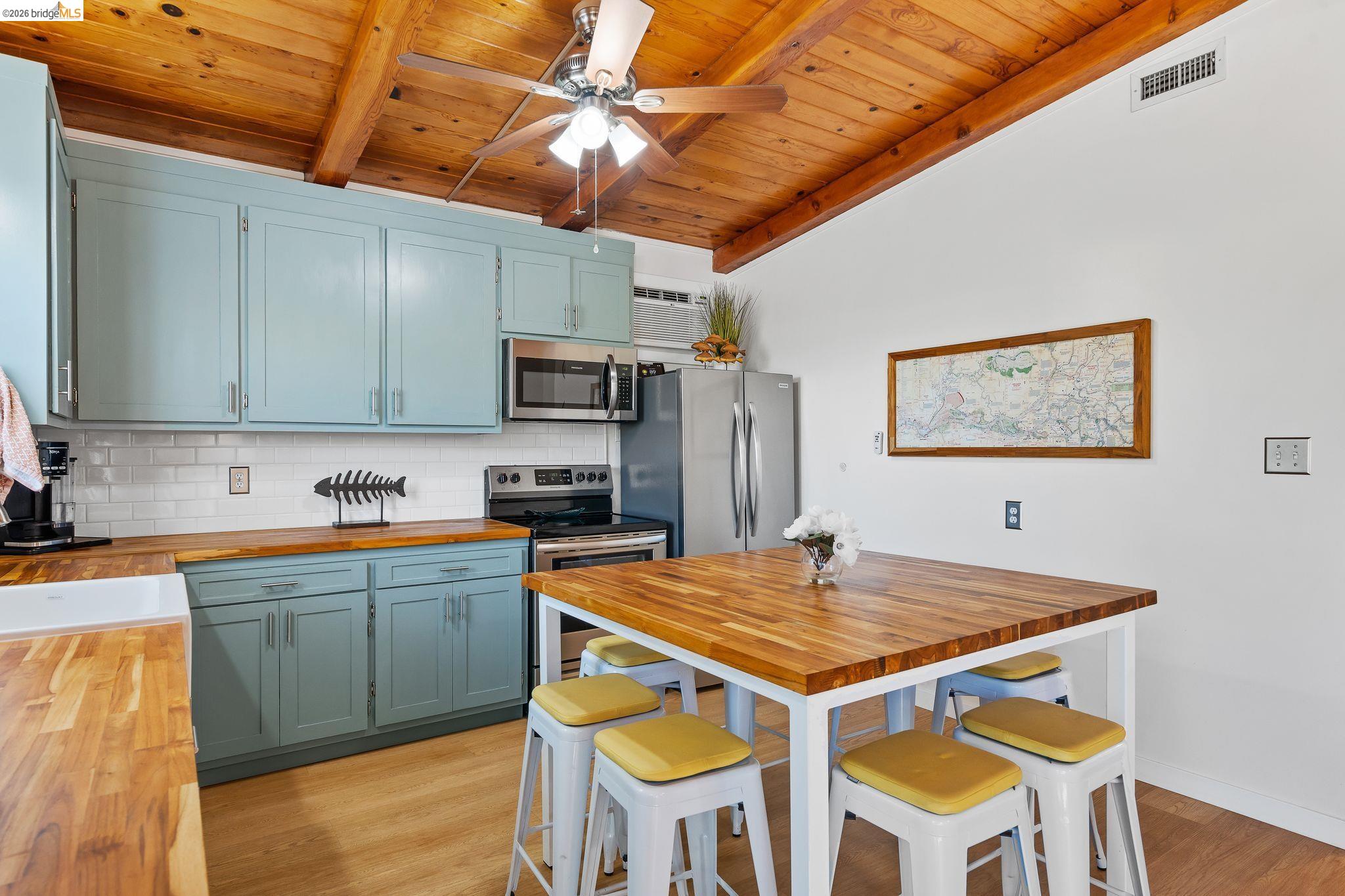 1704 Taylor Road Bethel Island, CA 94511 - Photo 29 of 73 Kitchen featuring a vaulted wood-paneled ceiling with exposed beams, light blue cabinetry, butcher block countertops, and stainless steel appliances