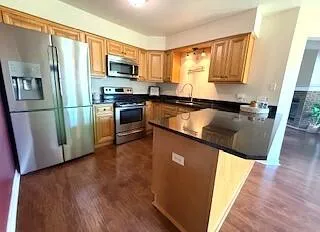 a kitchen with granite countertop a refrigerator stove top oven and sink
