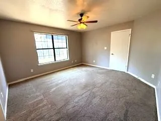 an empty room with windows and ceiling fan