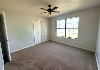 an empty room with windows and ceiling fan
