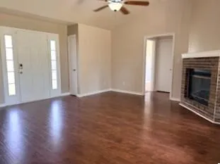 an empty room with wooden floor fireplace and windows