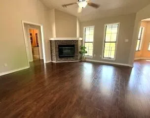 an empty room with wooden floor fireplace and windows