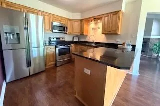 a kitchen with stainless steel appliances granite countertop a refrigerator a stove a sink and a microwave