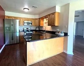 a kitchen with stainless steel appliances granite countertop a refrigerator a stove top oven a sink and dishwasher with wooden floor
