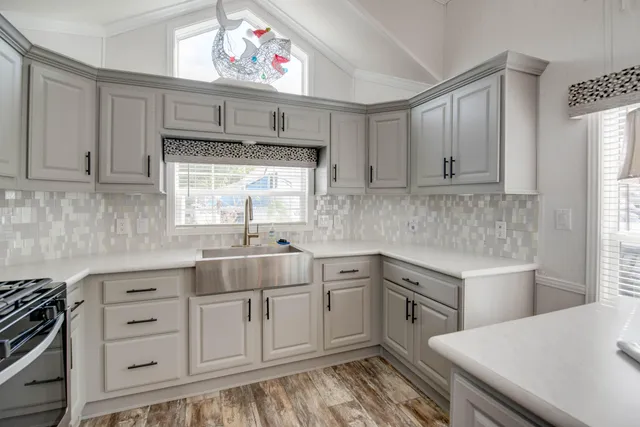 a kitchen with stainless steel appliances granite countertop a refrigerator a sink a stove and a refrigerator with wooden floor