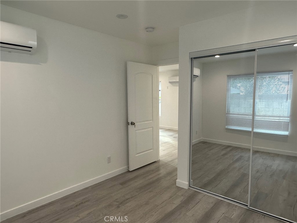 7012 Bertrand Avenue Reseda, CA 91335 - Photo 9 of 23 an empty room with wooden floor and mirror
