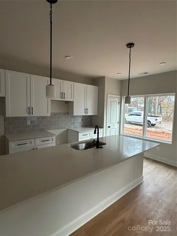 a kitchen with stainless steel appliances a refrigerator a sink a stove a dining table and chairs with wooden floor