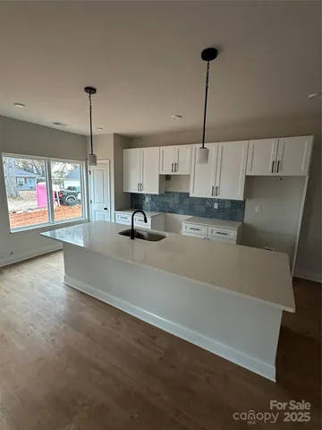 a kitchen with stainless steel appliances kitchen island a sink a stove a refrigerator and white cabinets