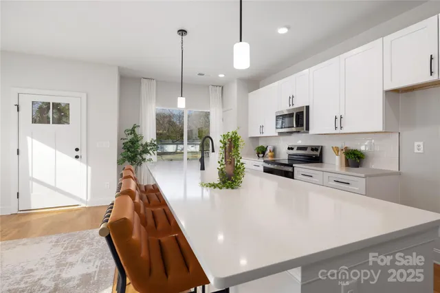 a view of a kitchen with kitchen island a counter top space a sink stainless steel appliances and cabinets