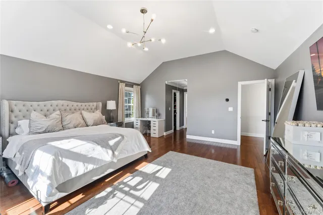 a spacious bedroom with a bed and a flat tv screen on dresser