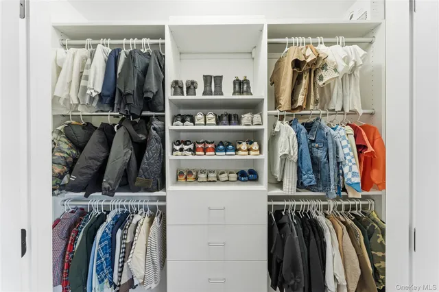 a view of walk in closet with clothes and shoes