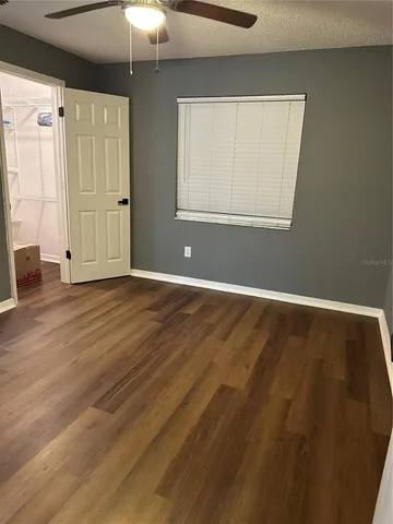 an empty room with wooden floor cabinet and windows